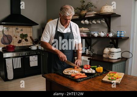 Caucasian male cooking in kitchen chopping vegies Stock Photo