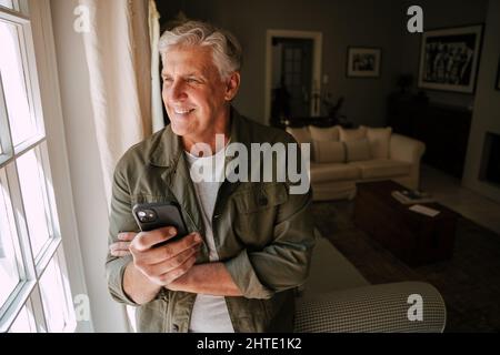 caucasian senior male holding cellular device relaxing in lounge Stock Photo