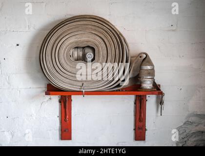Old fashioned fire house on wall of retro business mill warehouse.  Brass coupling and material house pipe. Stock Photo