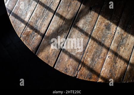 Sun shining through glass paned sash window hasting shadow over solid oak wooden table on summers day. Stock Photo