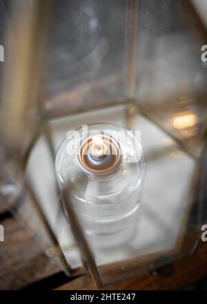 Oil candle burning from wick in a beautiful glass housing.  Orange flame flickering before wedding ceremony to act as romantic decoration for marriage Stock Photo