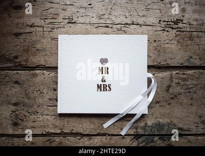 Mr Mrs bride and groom guestbook with beautiful Diamond crystal love heart on solid oak retro vintage wooden table. Stock Photo