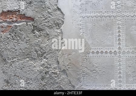 Damaged plaster on brick wall background. Brickwork under crumbling texture concrete surface. Stock Photo