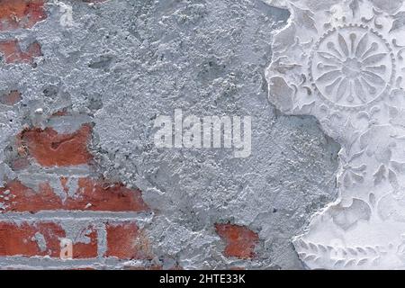 Damaged plaster on brick wall background. Brickwork under crumbling texture concrete surface. Stock Photo