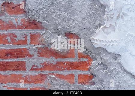 Damaged plaster on brick wall background. Brickwork under crumbling texture concrete surface. Stock Photo