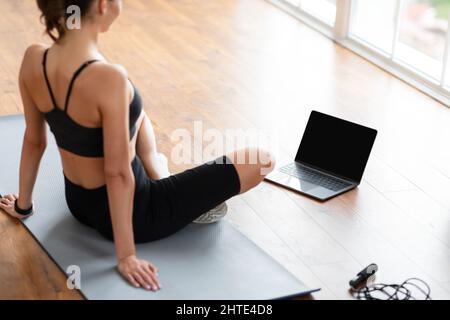 Young black woman sitting on mat with blank pc Stock Photo