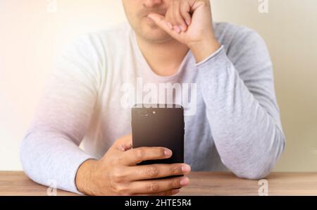 Man holding smartphone and beating his nails due to stress, anxiety and worried. Stock Photo