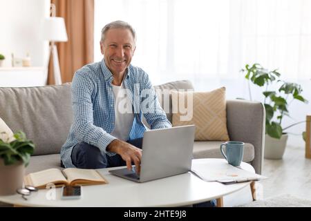 Confident smiling mature using laptop at home Stock Photo
