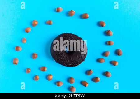 Donut with hazelnuts on a blue background, close up Stock Photo