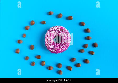 Donut with hazelnuts on a blue background, close up Stock Photo