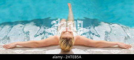 Relax, unwind and get into a blissful state of mind. Rearview shot of a young woman relaxing in the pool at a spa. Stock Photo