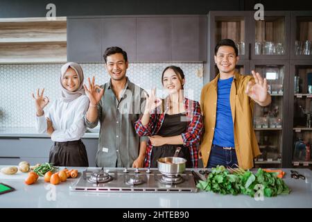 friends preparing to cook in the kitchen together showing thumb up Stock Photo