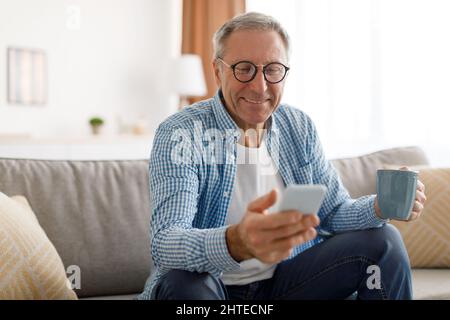 Portrait of smiling mature man using smartphone at home Stock Photo