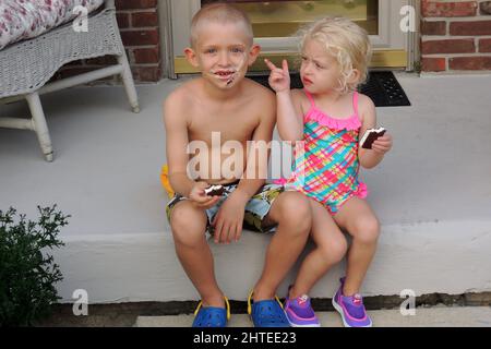View of male and female kids eating sandwich ice cream and having fun Stock Photo