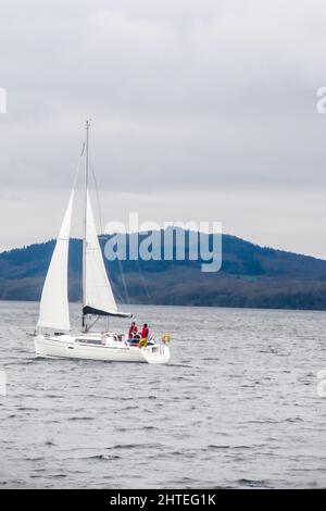 A Single mast Sailboat on Windermere Lake, in the Lake District, UK, on a grey, windy overcast day Stock Photo