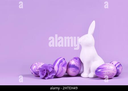 Easter eggs next to bunny figure on violet background Stock Photo