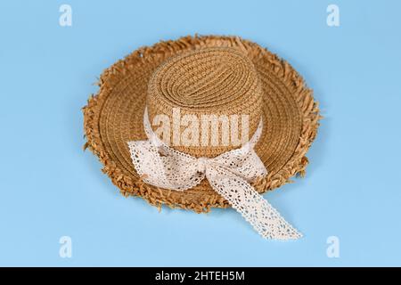 Summer straw hat with lace ribbon on blue background Stock Photo