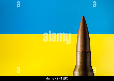 Bullet isolated on the Ukrainian flag background. Russia and Ukraine war concept. Stop war. Stock Photo