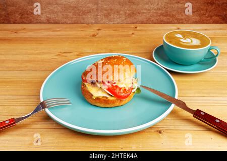 Bagel with chicken, tomato and cheese on wooden table. Stock Photo