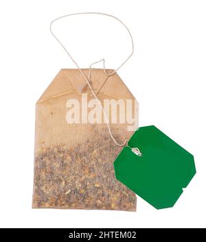 Brown un used tea bag with green emty label on a white string. Isolated on a white background. Stock Photo