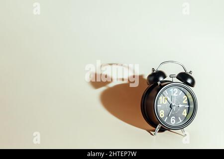 Black alarm clock with dial on beige background. Concept of time and timing with space for copying. Background. Stock Photo