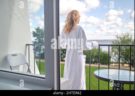 A blonde woman in a white robe looking relaxed and thoughtful Stock Photo