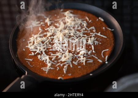 Delicious rosy pancake with melted cheese lies on frying pan. Classic recipe. Traditional homemade cakes. Nutritious breakfast. background. Stock Photo