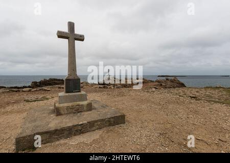 Cross at the Normandy seaside with a lighthouse in the background Stock Photo