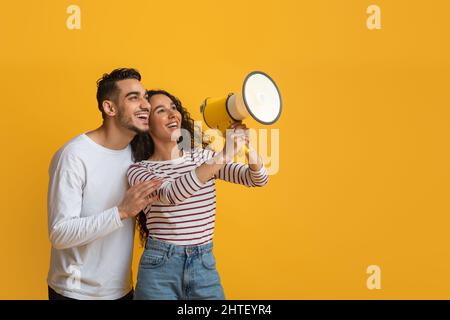 Nice Promo. Cheerful Arab Couple Using Megaphone For Making Announcement Stock Photo