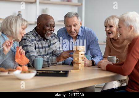 Emotional seniors playing jenga, having fun at sanatorium Stock Photo