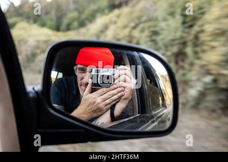 Person taking self portrait in rearview mirror of car while driving Stock Photo
