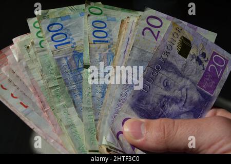 Closeup of a hand holding Swedish currency different banknotes with black background Stock Photo