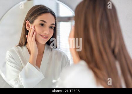 Natural Beauty. Portrait Of Attractive Female Smiling To Her Reflection In Mirror Stock Photo
