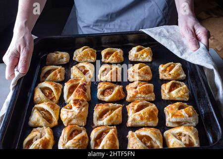 a woman holds a baking sheet with baked homemade cookies with fr Stock Photo