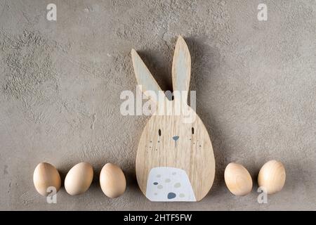 eggs and rabbit made of wood on beige plaster, copy space Stock Photo
