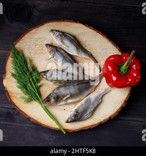 Sun dried fish, salted smelts over wooden background, top view Stock Photo
