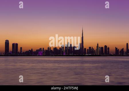 Skyline of Dubai Downtown after sunset during golden hour with purple sky and Dubai Creek Canal, long exposure. Stock Photo