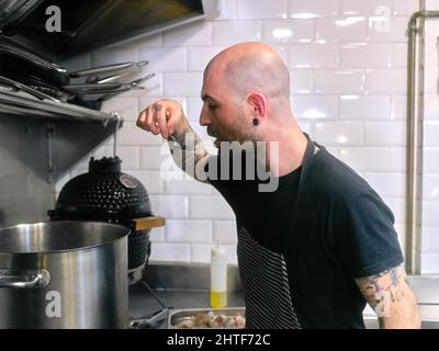 Chef tasting food from a pot while working in a restaurant kitchen
