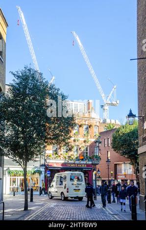 Tall white cranes seen against a blue sky in a London street scene. Stock Photo