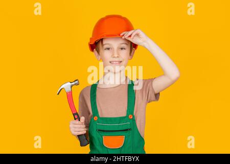 Child building helmet, hard hat. Hammer hammering. Little builder in helmet and hummer. Child dressed as a workman builder. little boy wearing helmet Stock Photo