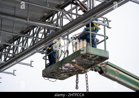 Scenic shot of unidentifiable operators working on a crane wearing safety clothing Stock Photo