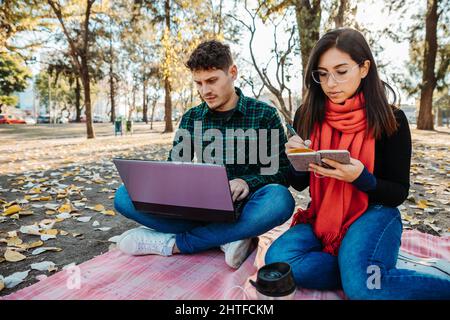 young couple using laptop to work outdoors Stock Photo