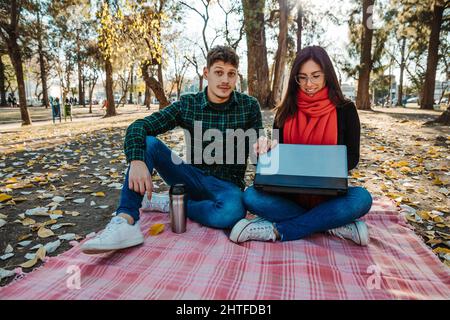young couple using laptop to work outdoors Stock Photo