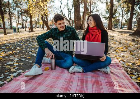 young couple using laptop to work outdoors Stock Photo