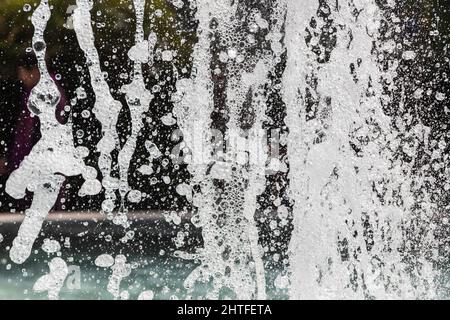 Jets of water with a lot of drops and bubbles under the rays of the sun on a blue background. A large plan The texture of the water waves of a large f Stock Photo