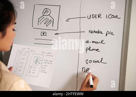 UX designer writing ideas for improving mobile application interface on whiteboard Stock Photo