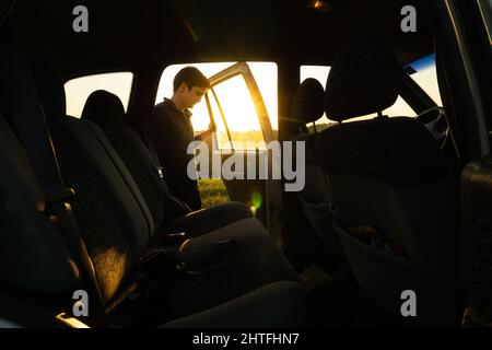 Closeup shot of a Hispanic young male opening the car door during the sunrise Stock Photo