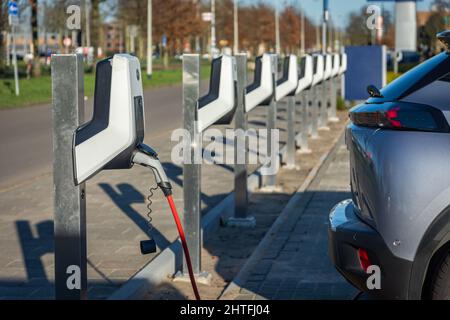 Electric car charging station in The Netherlands, focus on plugged charger Stock Photo
