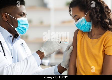 African american doctor making vaccination for teen girl Stock Photo