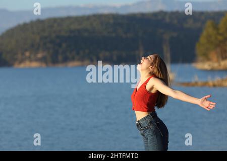 Profile of an excited woman in red screaming outstretching arms in a lake Stock Photo